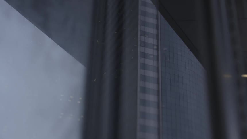 Skyscraper in city downtown reflected on a tinted window