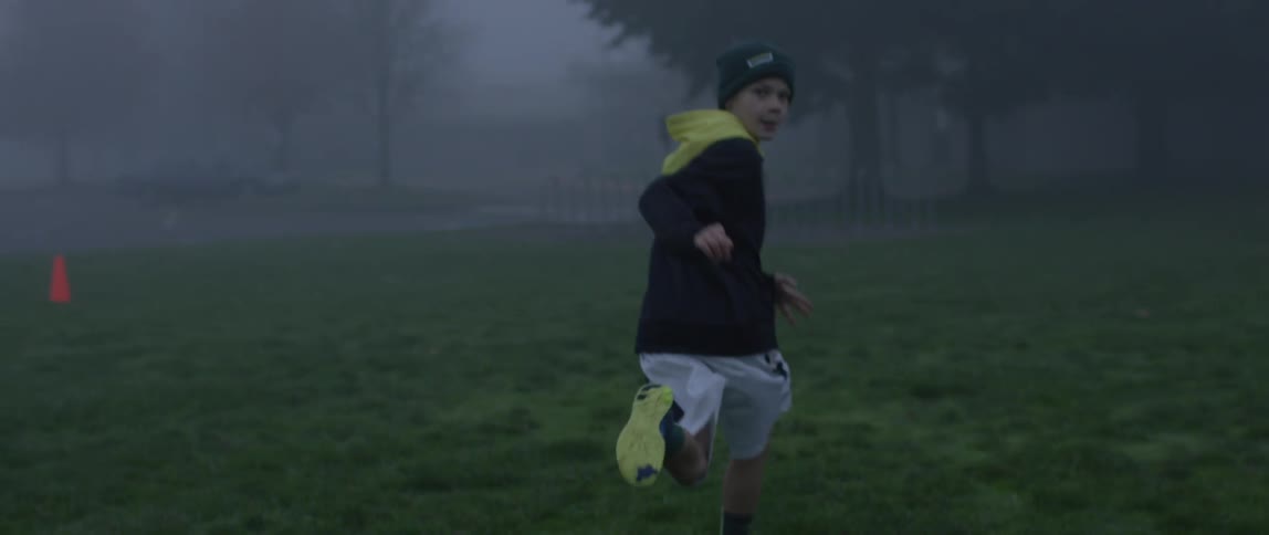 Young boys running through a field on a rainy night