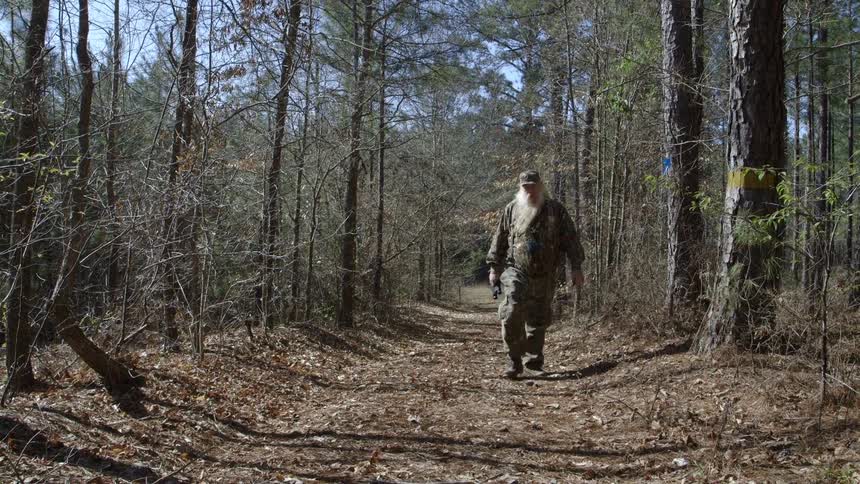 A man walks down a path in the woods