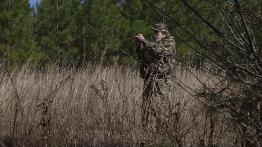 A person in camo staying in the grass
