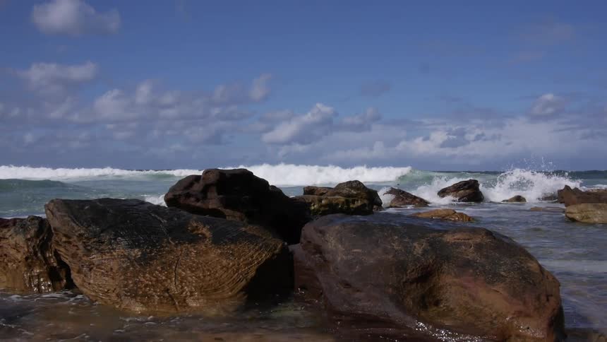 Ocean waves crash into rocks on a seashore