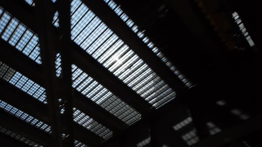 An upward view of skyscrapers and the sun while going under a bridge