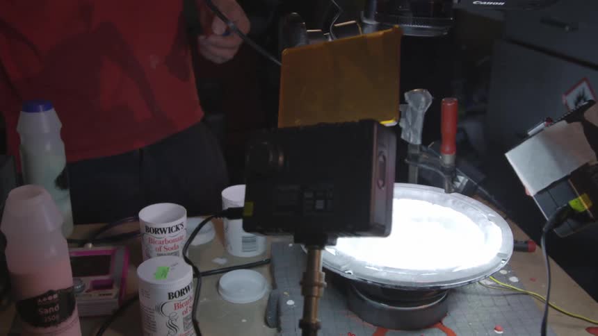 A young man uses sound to create sand patterns in a small studio
