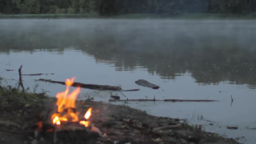 A fire is burning near a lake