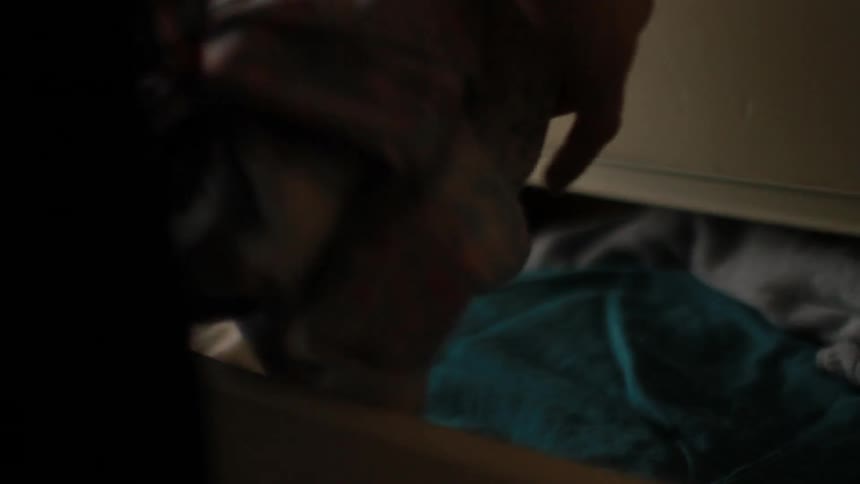 Woman opens drawer and gets a shirt out