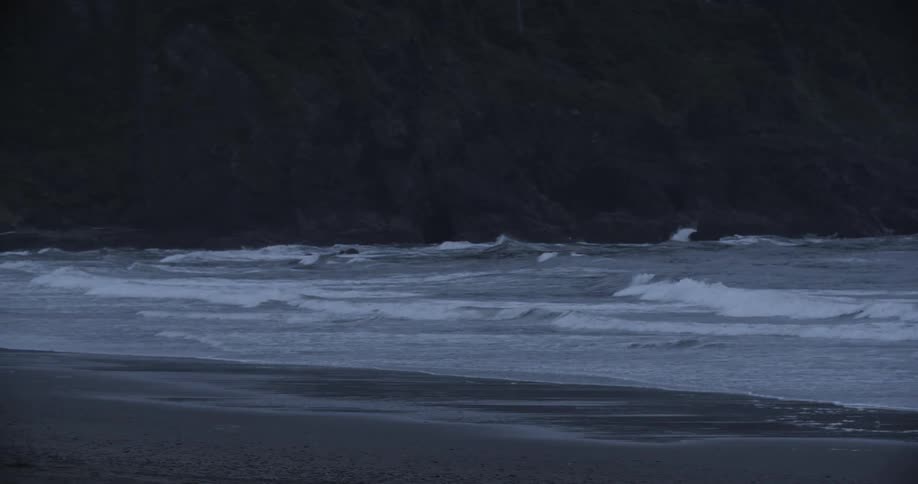 Waves wash up on beach with rocky cliffs