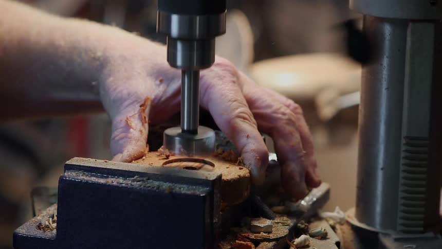 A man uses a drill press