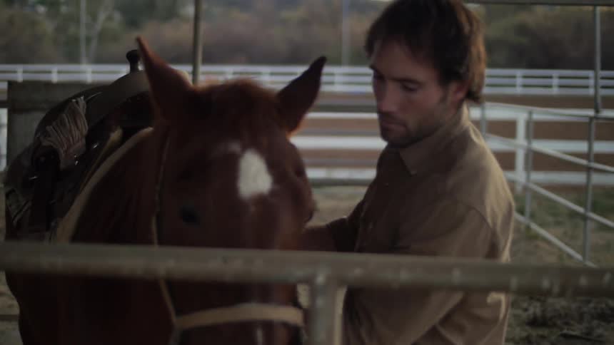 A man putting a pad on the horse back