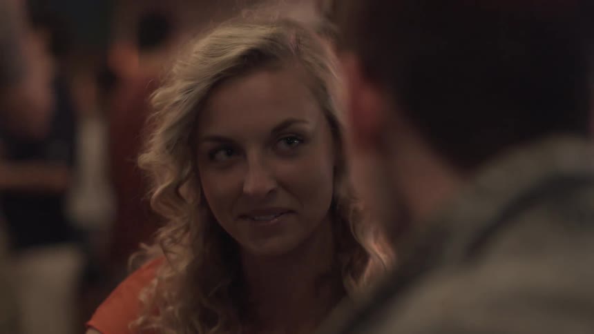 Blonde woman laughs and talks with a man in a busy restaurant