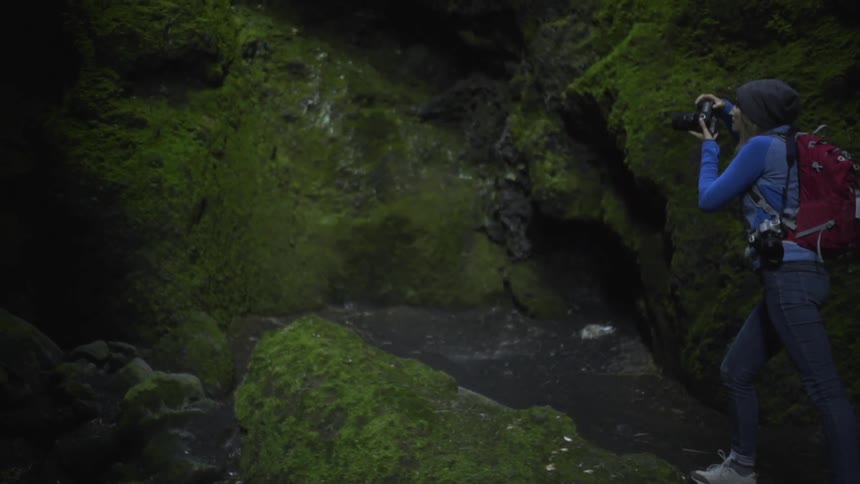 Water flows down rocks as a woman walks up them to take a picture