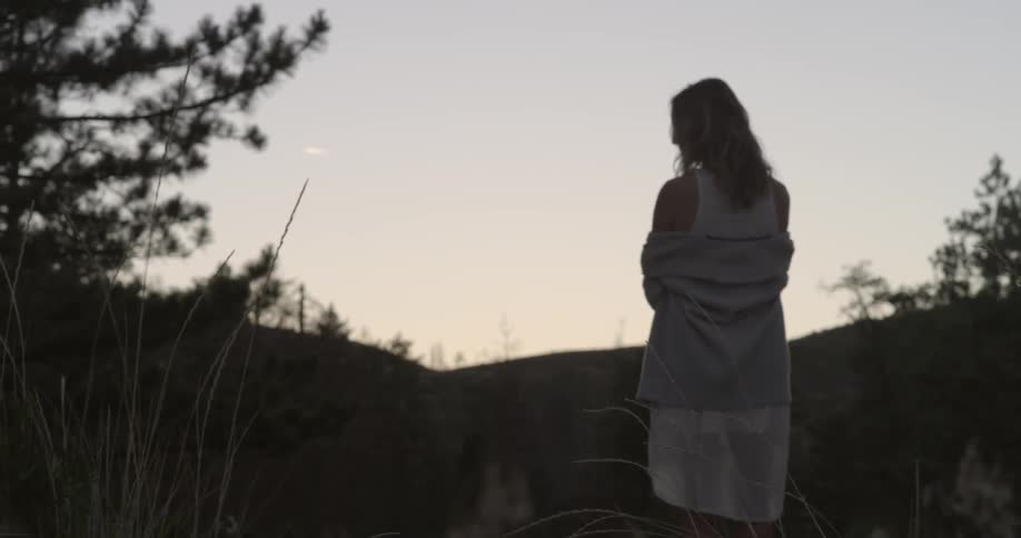 A woman stands outdoors with her back turned