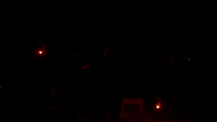 A firework is launched from the ground and spews sparks and smoke