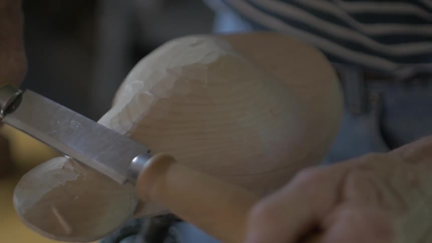A man shaves a piece of wood