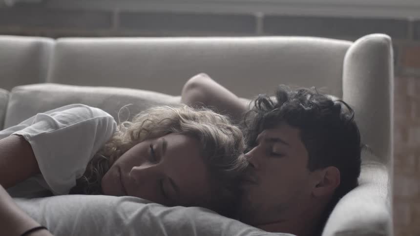 A man and woman cuddle on the couch