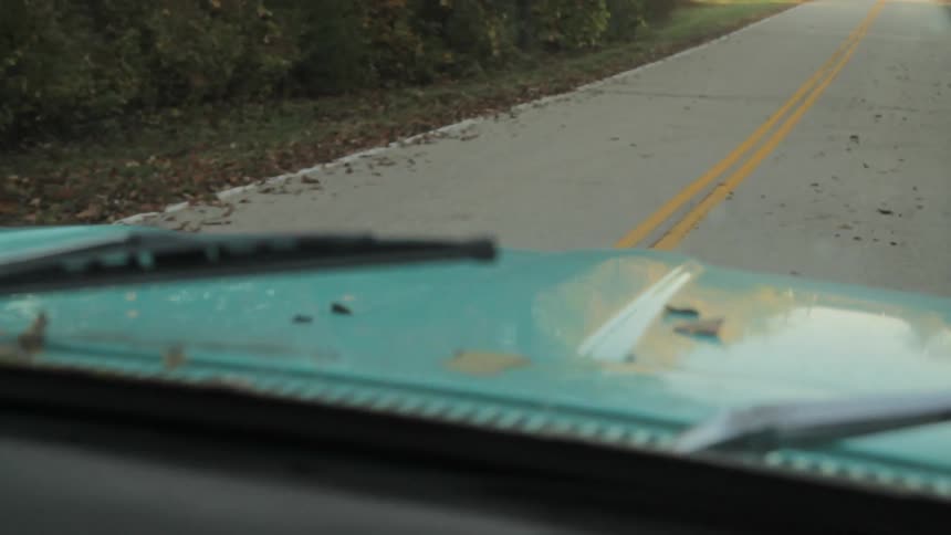 A blue truck is driving down a road