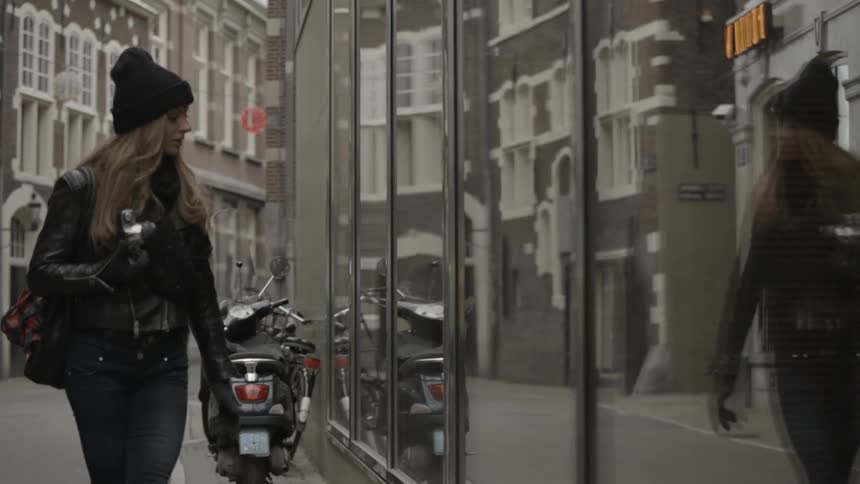 A woman with a camera window shops in a city