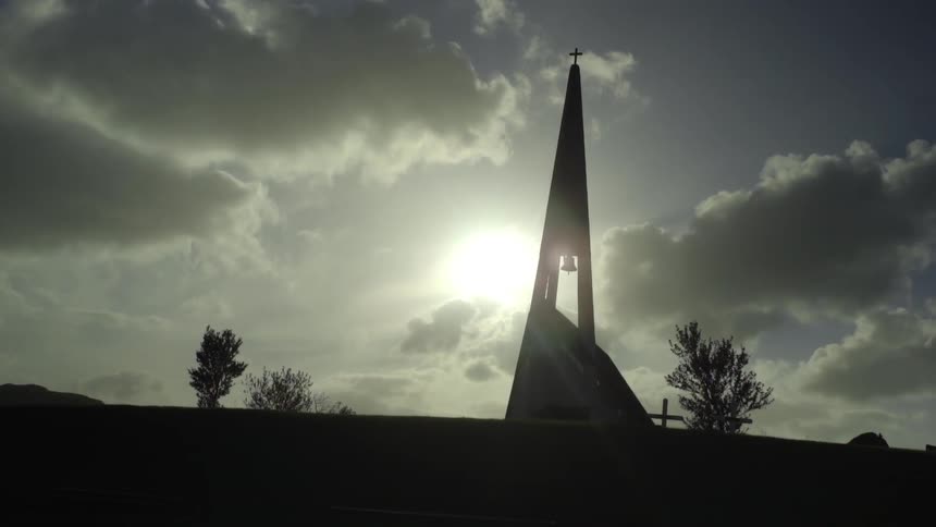 A tall tower has a cross at the top