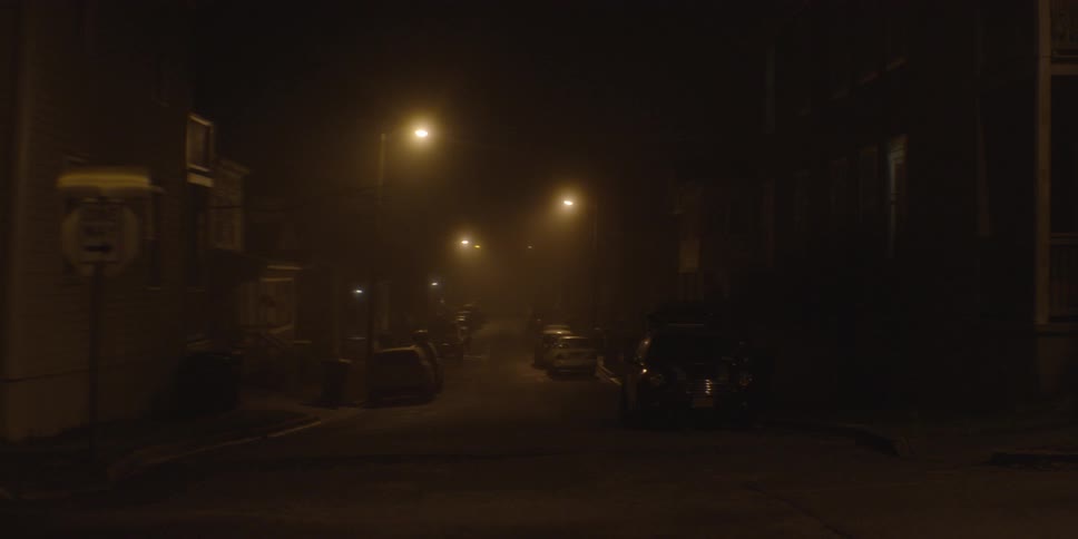 Cars parked up and down a street lit by street lights