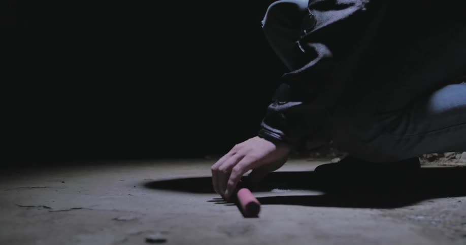 A man in a motorcycle helmet bends down to pick up an object from the floor
