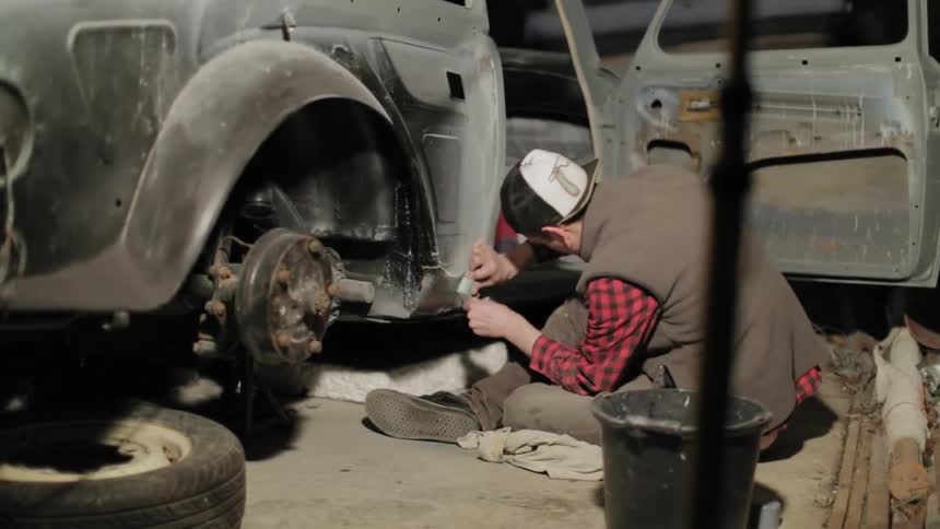 A man works at restoring an old pickup