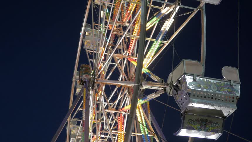 Closeup of an empty ferris wheel at night with its lights flashing