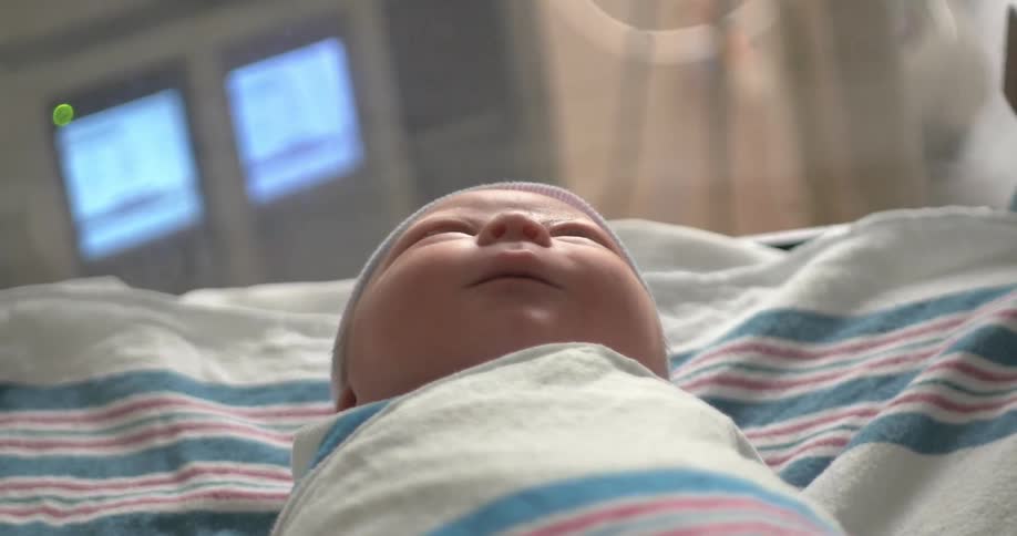 A new born baby is resting on a hospital bed