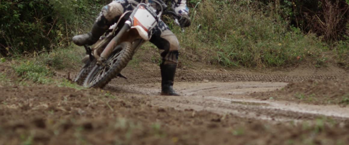 A person rides a dirt bike around a curve on a dirt track