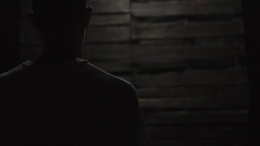Man walking toward a wall inside a dark building