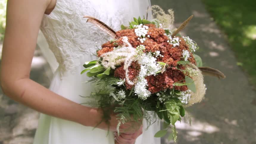 A bride stands while holding a bouquet