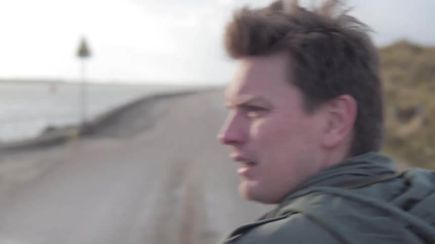 A man walks down a beachside road