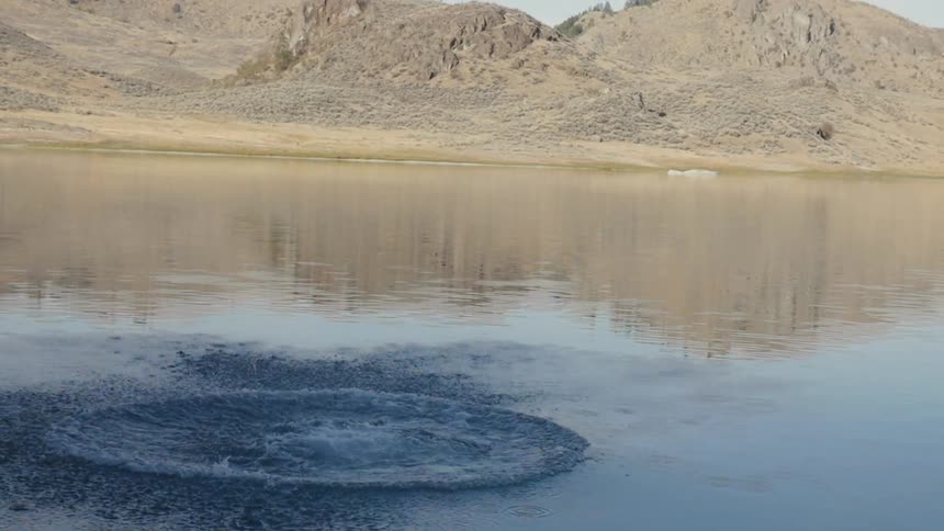 A man backflips off a cliff into a lake
