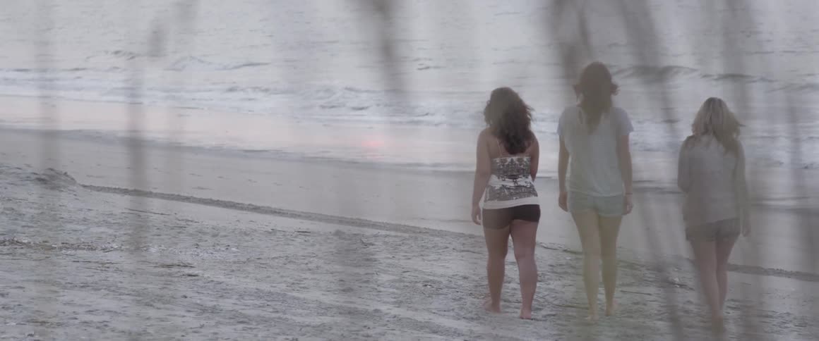 Three women walk together on the beach