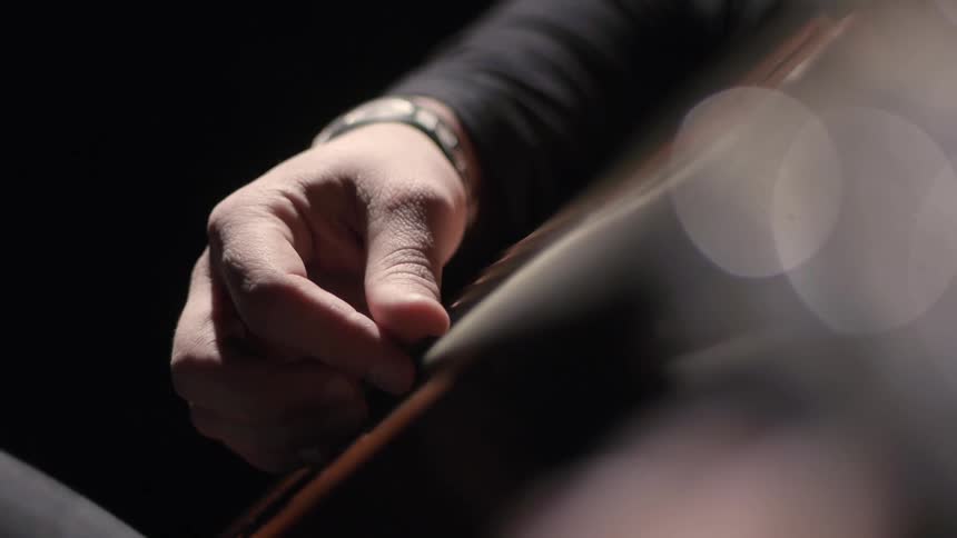 Person playing the guitar in a dark room