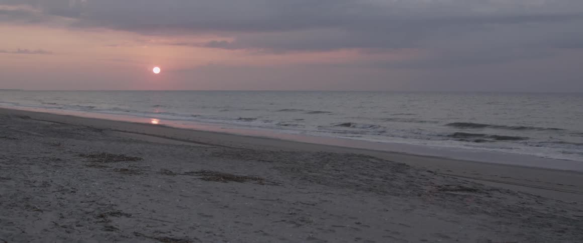 Waves crashing onto shore at sunset