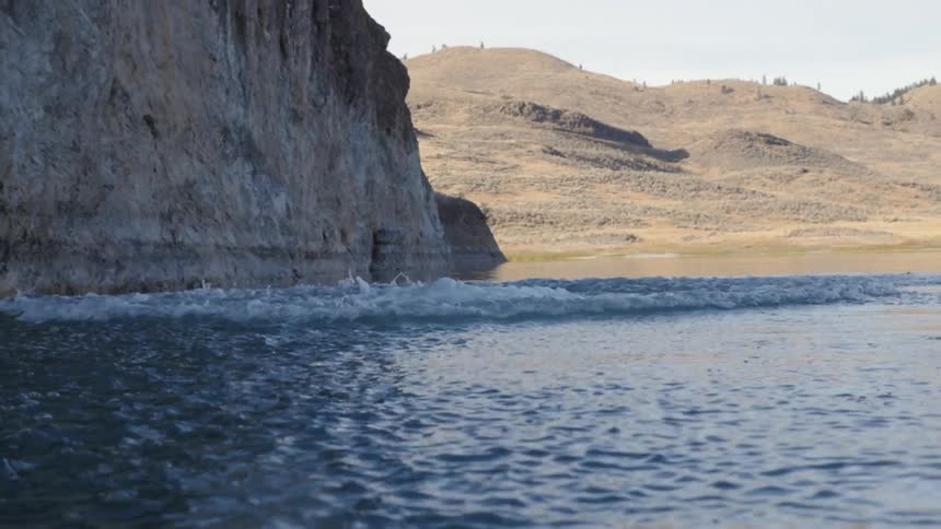 A man backflips off a cliff into a lake