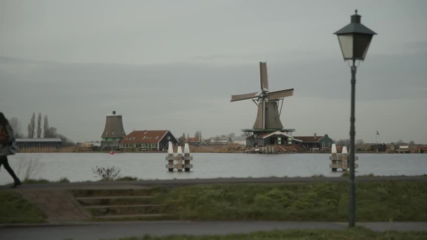People walk down a path while a windmill spins in the background