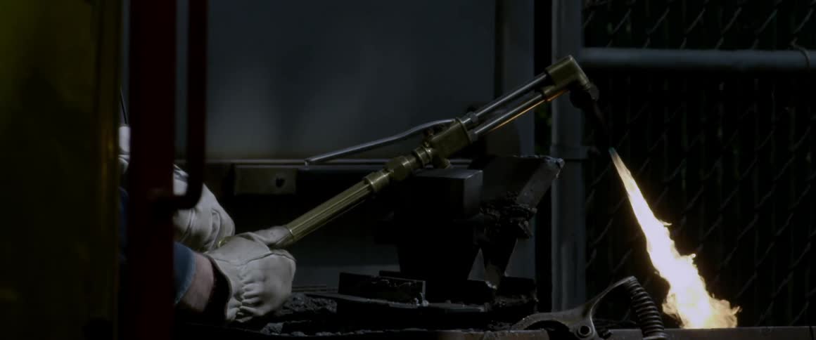 Gloved hands start a blowtorch