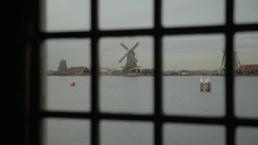 Windmills are shown in the distance through a window pane