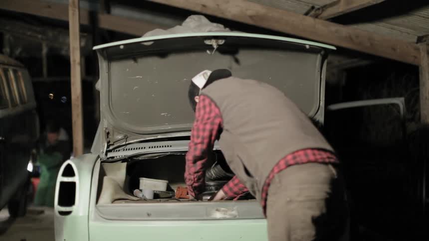 A man tinkers in the trunk of a car