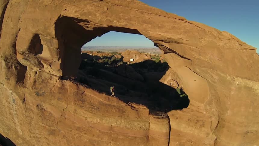 A backpacker walks down a cliff in Utah