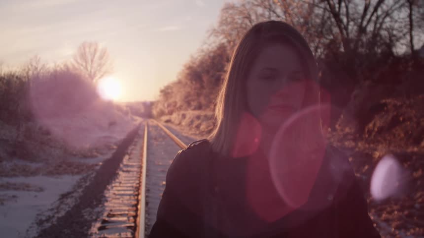 A woman stands on the train tracks