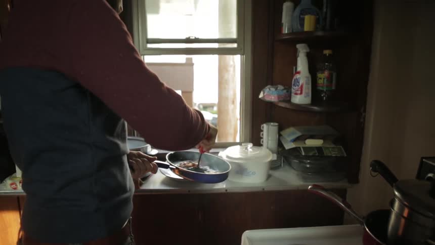 Man walks through the house to the kitchen to cook bacon