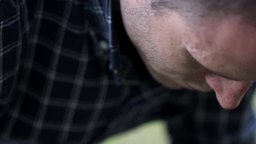 A man in a flannel shirt bending over