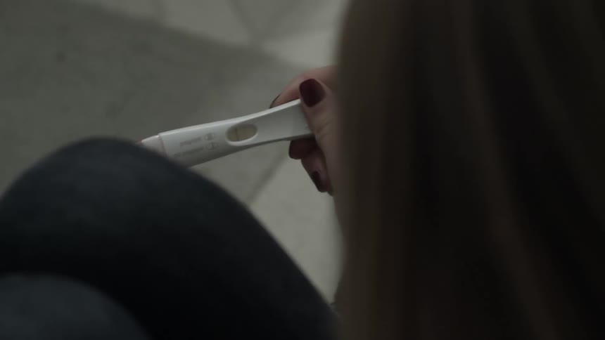 A woman holds a positive pregnancy test