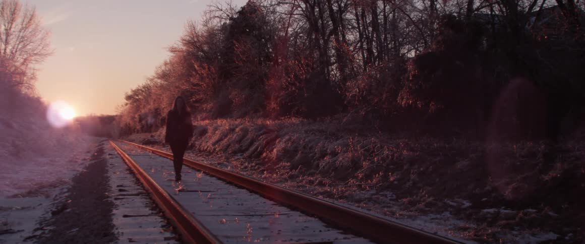 A person walking along the train tracks
