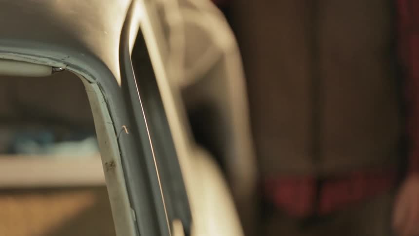 A man covers an old car