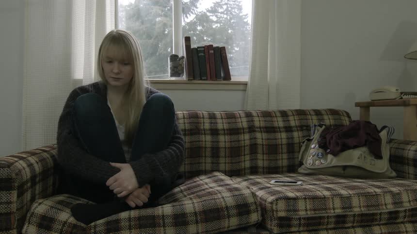 Depressed woman sitting alone on a couch