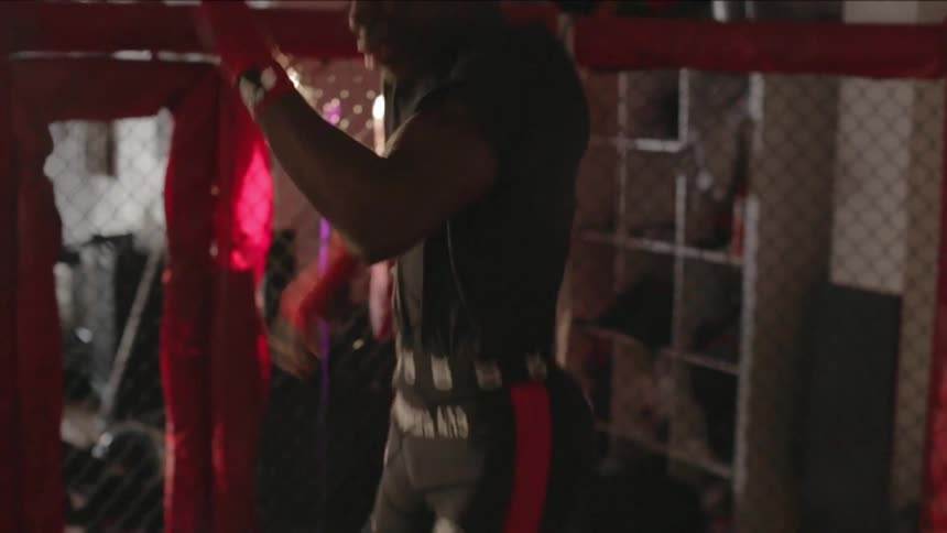 A man practices jump kicks in a boxing cage