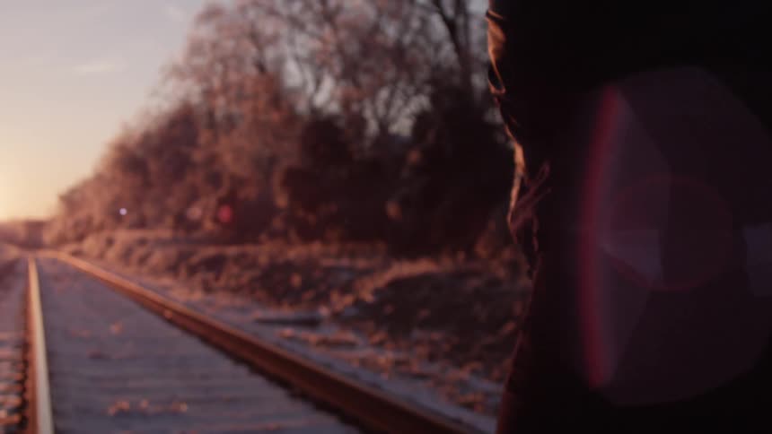 A person walking along the train tracks