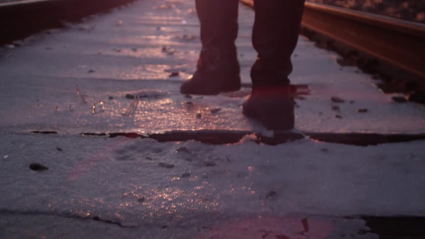 A person walking in snow on the railroad tracks